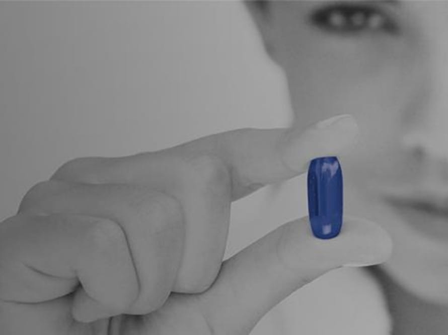 Afbeelding van een hand die een blauwe Pileje supplement capsule vasthoudt voor kennistraining.
